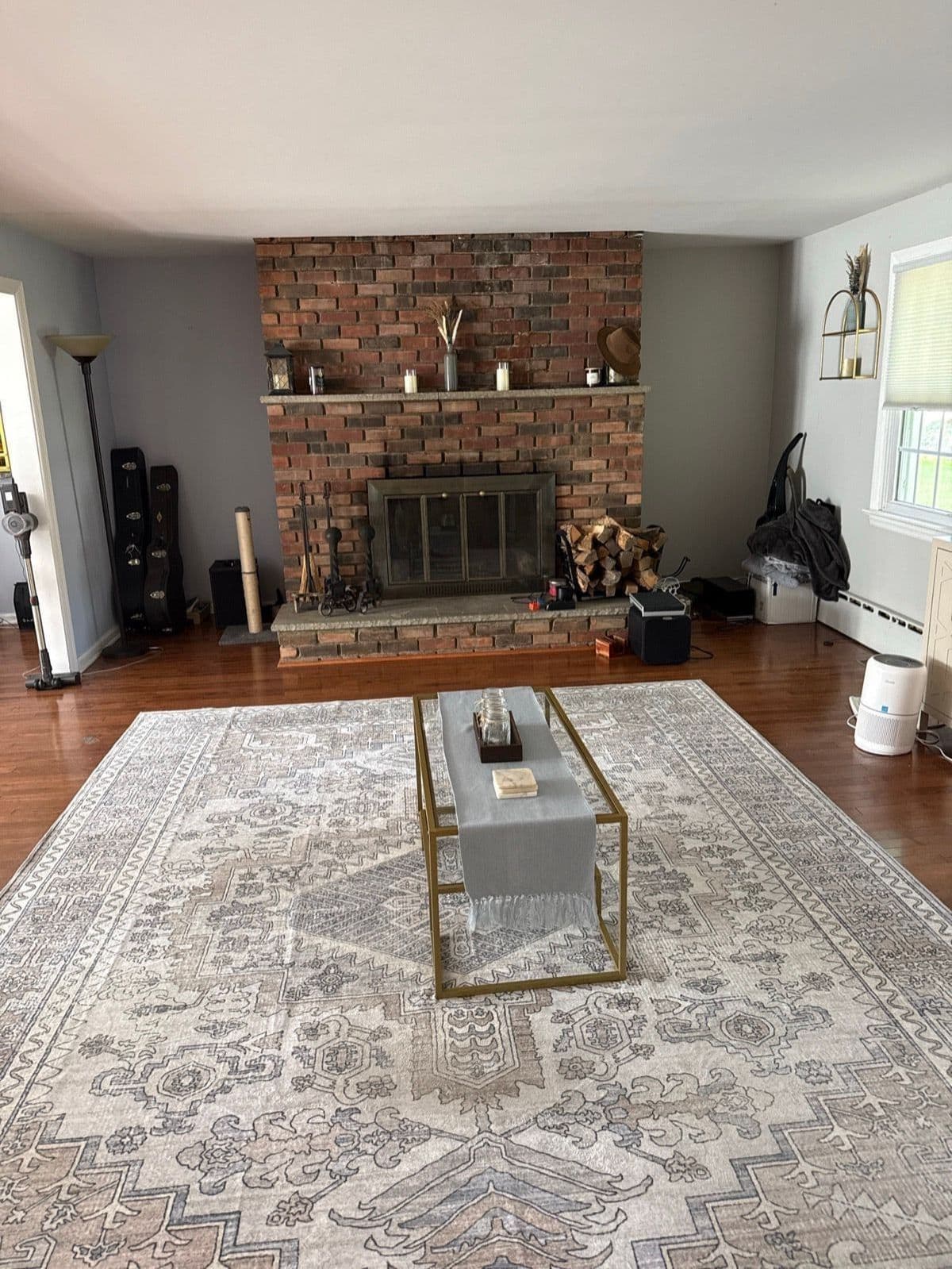 The living room before: brick fireplace, vintage-style rug, and no seating